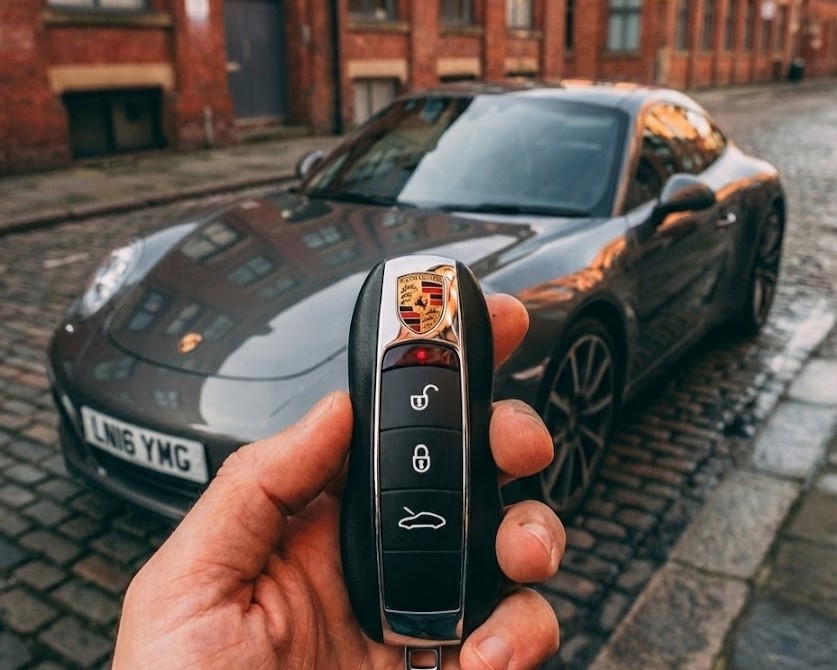 Porsche sports car with new key held in front